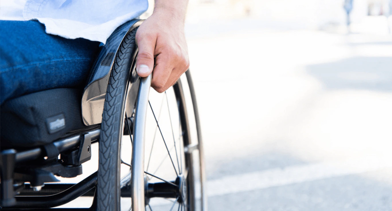 Close-up of a person's hand on the wheel of a wheelchair
