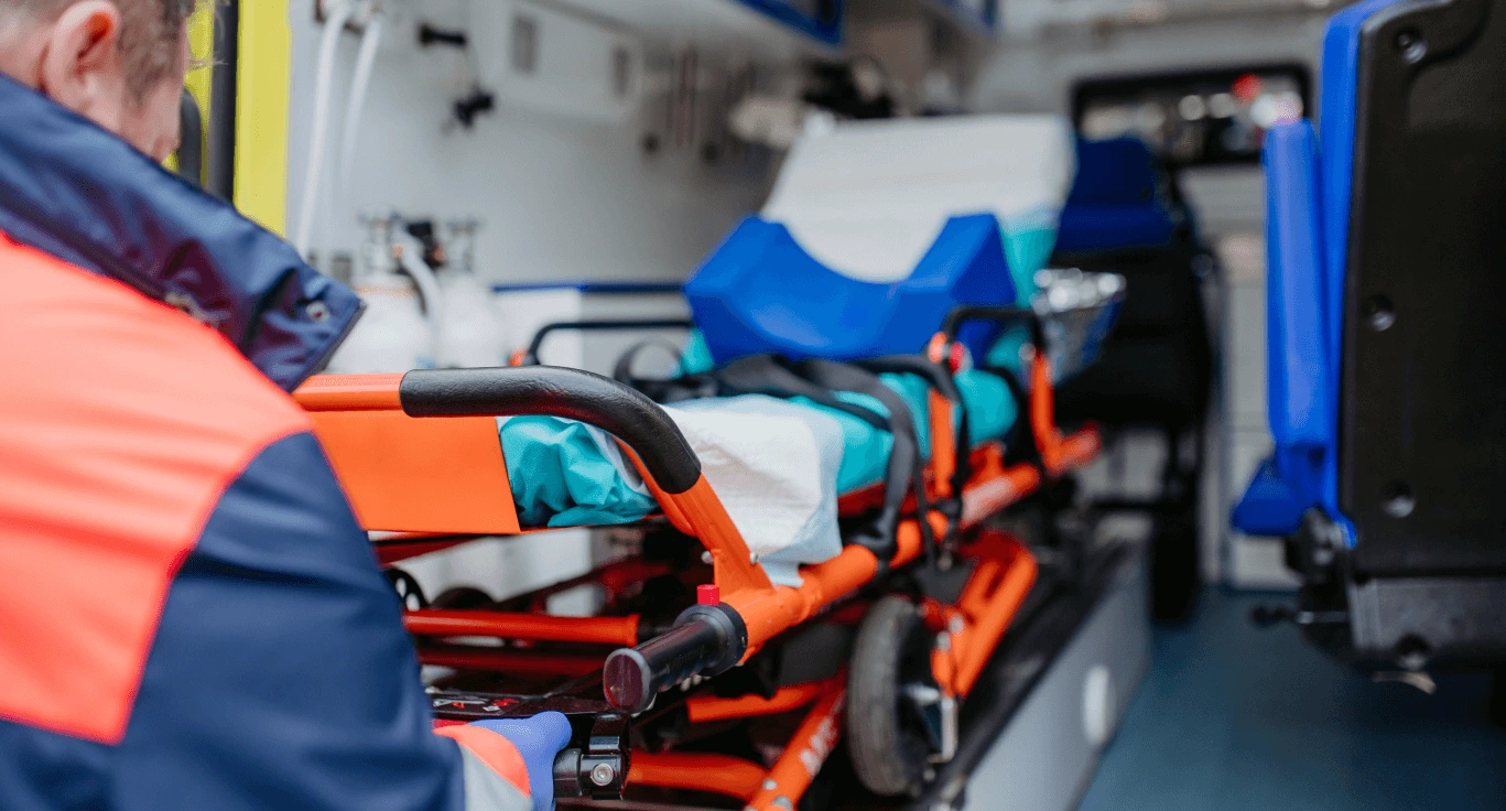 Stretcher with blue padding inside a medical transport vehicle, with a crew member in the foreground